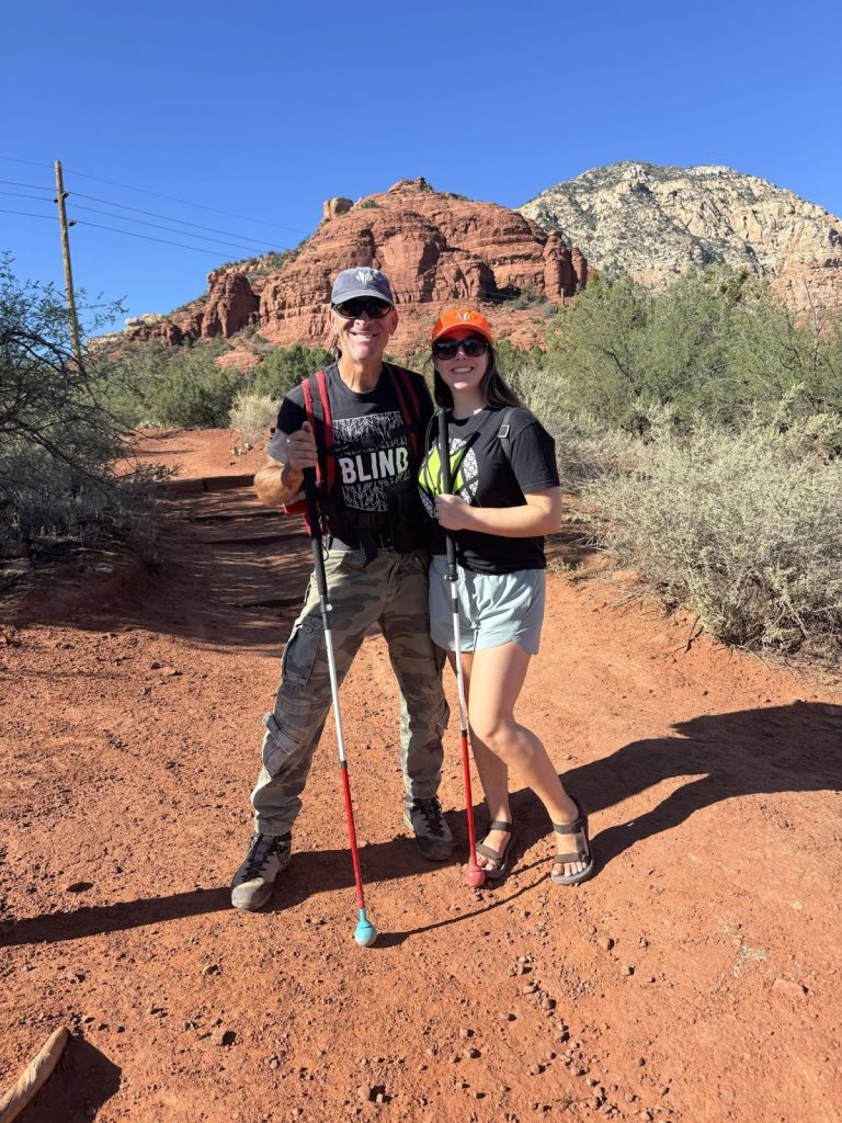 A photo of Dave and Monica posing for a picture in front of a rock in Sedona.
